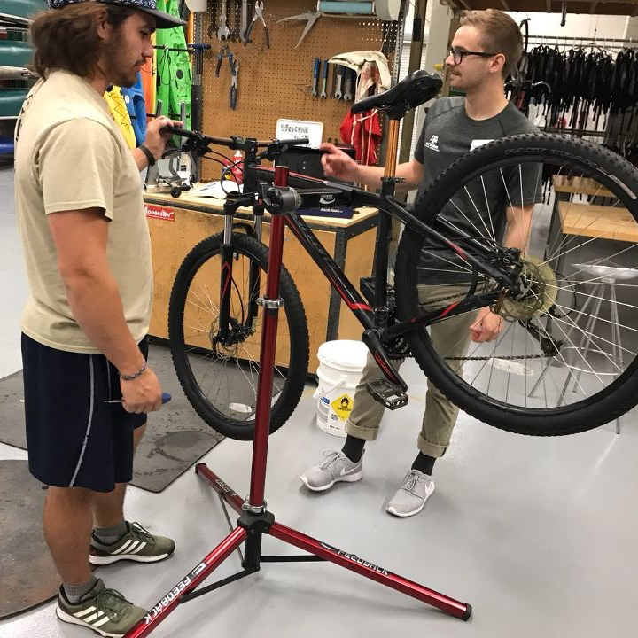 Two students repairing  a bike on a stand.