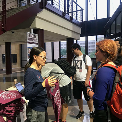 Students distributing tote bags to other students.